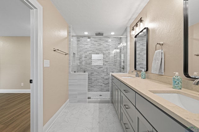 bathroom with marble finish floor, double vanity, a sink, and baseboards