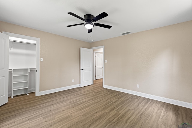 unfurnished bedroom featuring ceiling fan, visible vents, baseboards, a closet, and light wood finished floors