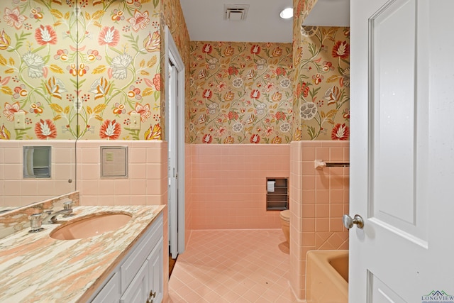 bathroom with vanity, a tub, tile walls, and tile patterned floors