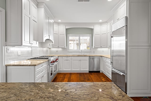 kitchen with white cabinetry, stone countertops, and premium appliances