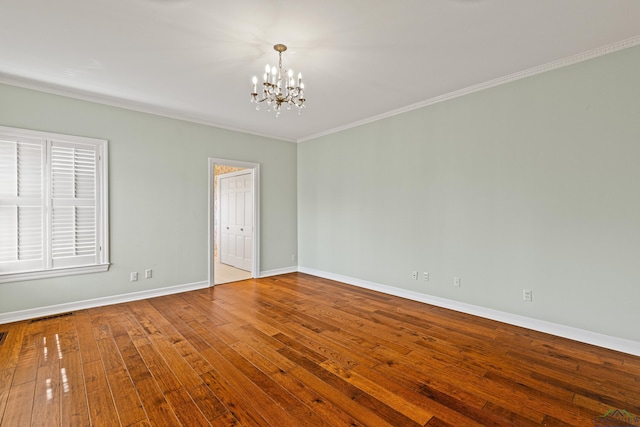 spare room featuring a notable chandelier, crown molding, and wood-type flooring