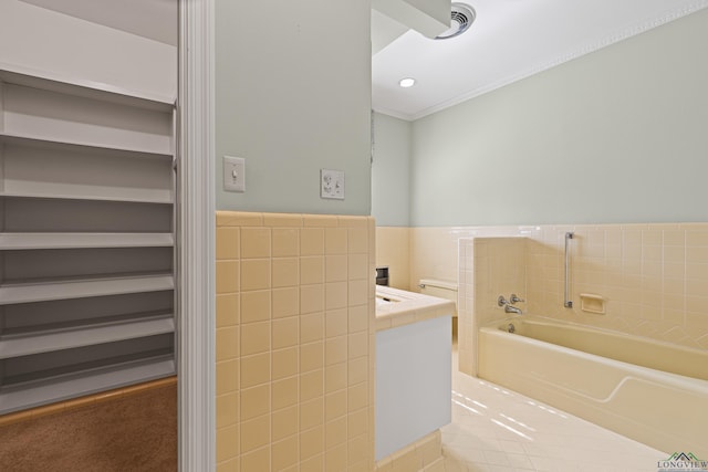 bathroom with vanity, tile walls, and a tub