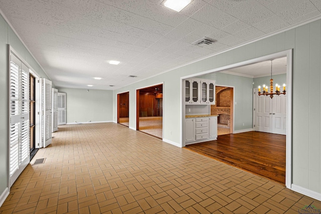 empty room featuring ornamental molding, a notable chandelier, and wood walls