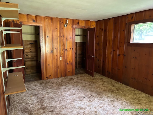 unfurnished bedroom featuring carpet flooring and wood walls