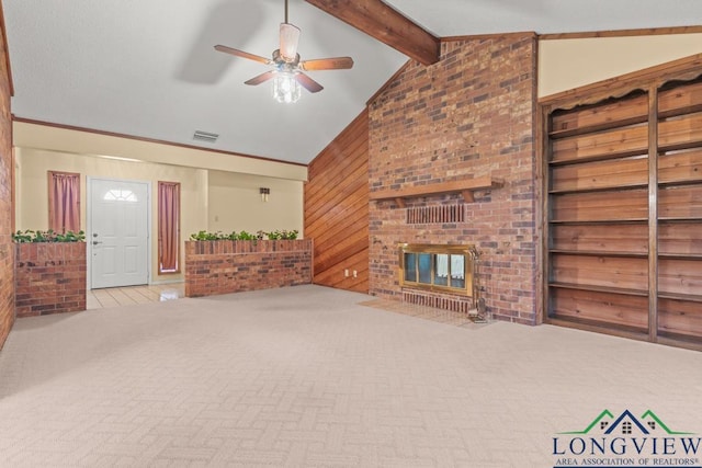 living room with wood walls, lofted ceiling with beams, a brick fireplace, ceiling fan, and light colored carpet