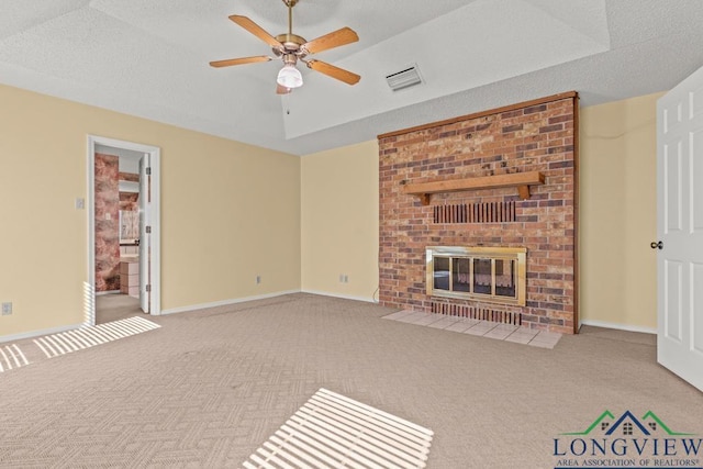 unfurnished living room featuring a fireplace, light carpet, a tray ceiling, and ceiling fan