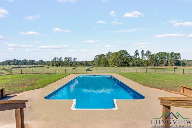 view of pool featuring a lawn and a rural view