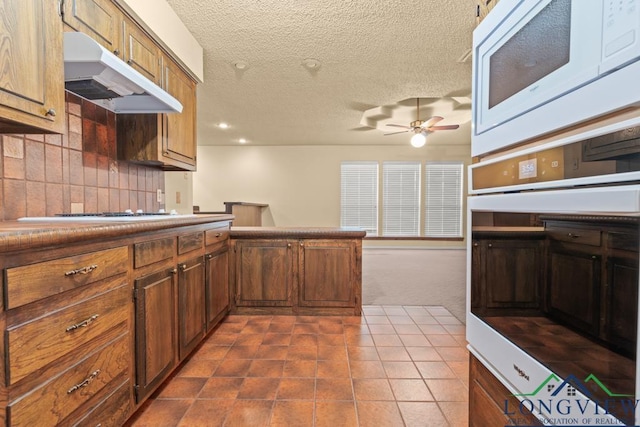 kitchen with carpet, white appliances, ceiling fan, a textured ceiling, and tasteful backsplash