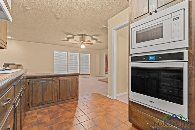 kitchen featuring carpet flooring, wall oven, a textured ceiling, white microwave, and ceiling fan