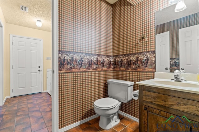 bathroom featuring a textured ceiling, vanity, and toilet