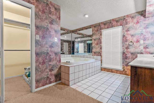 bathroom featuring tiled tub, tile patterned flooring, vanity, and a textured ceiling