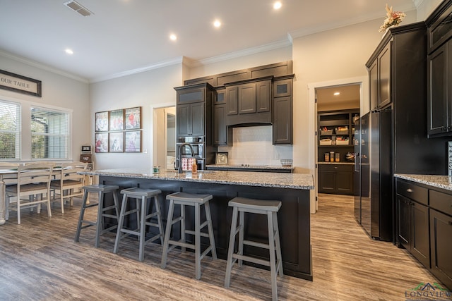 kitchen featuring light stone countertops, light hardwood / wood-style flooring, and an island with sink