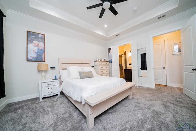 carpeted bedroom with ceiling fan, a raised ceiling, crown molding, and connected bathroom