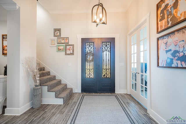 entrance foyer with hardwood / wood-style floors, an inviting chandelier, ornamental molding, and french doors