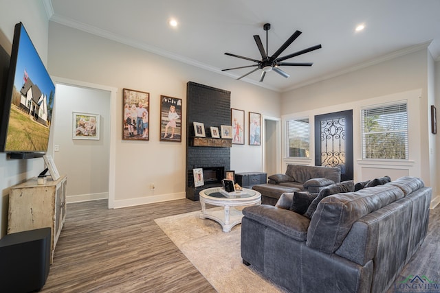 living room with dark hardwood / wood-style floors, a brick fireplace, ceiling fan, and crown molding