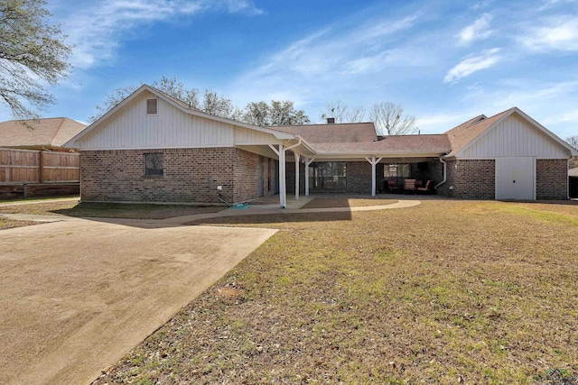 rear view of property featuring a yard, fence, and brick siding