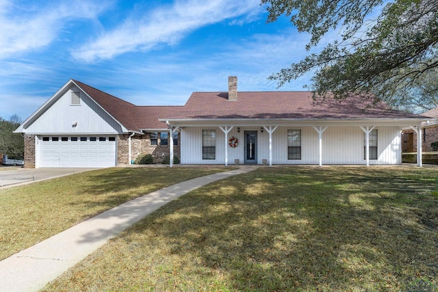 view of front facade with driveway, a chimney, an attached garage, and a front yard