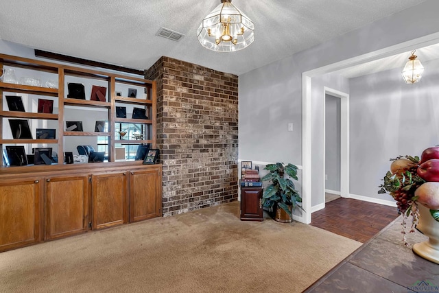 office area featuring baseboards, visible vents, brick wall, a textured ceiling, and a notable chandelier