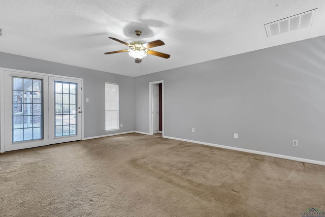 unfurnished room with carpet floors, visible vents, ceiling fan, a textured ceiling, and baseboards