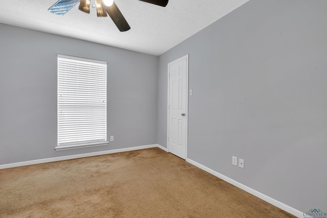 empty room with a textured ceiling, ceiling fan, carpet flooring, and baseboards