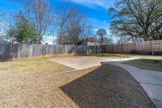 view of yard featuring a fenced backyard and basketball hoop