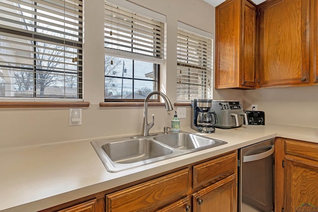 kitchen featuring dishwasher, light countertops, a sink, and brown cabinets