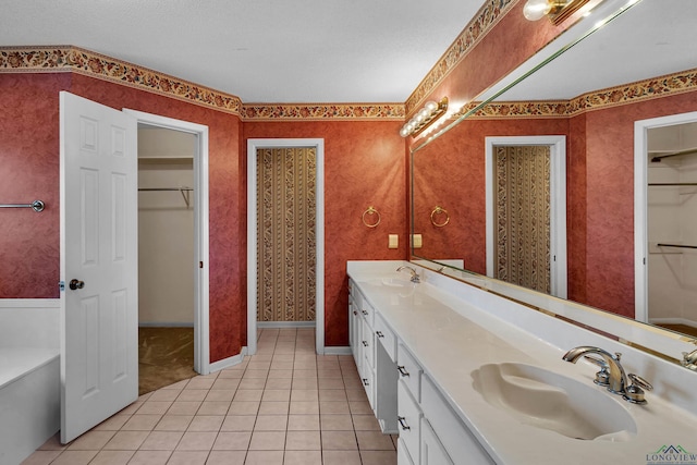 full bathroom with double vanity, a spacious closet, a sink, and tile patterned floors