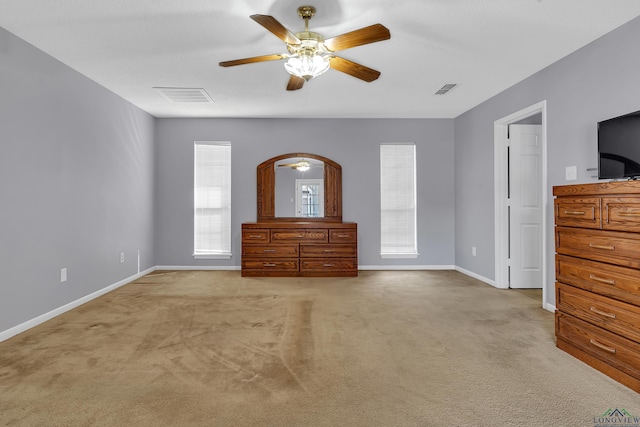 unfurnished bedroom featuring baseboards, a ceiling fan, visible vents, and light colored carpet