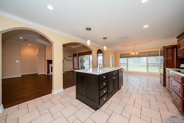 kitchen with a center island with sink, a healthy amount of sunlight, sink, and hanging light fixtures