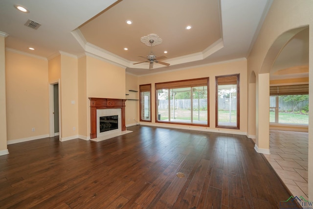 unfurnished living room featuring ceiling fan, crown molding, a fireplace, and a tray ceiling