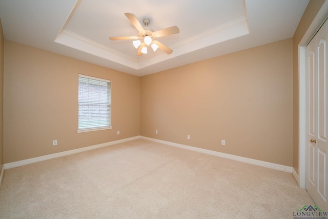 unfurnished bedroom featuring light carpet, a raised ceiling, and ceiling fan