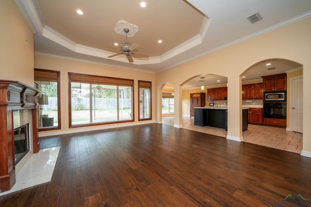 unfurnished living room featuring ceiling fan, a healthy amount of sunlight, and a tray ceiling