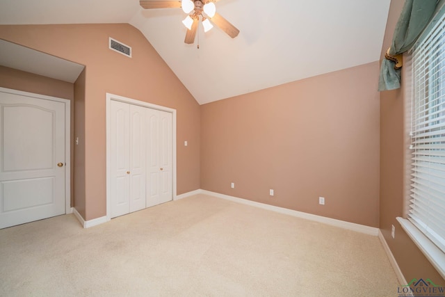 unfurnished bedroom featuring a closet, vaulted ceiling, ceiling fan, and light colored carpet