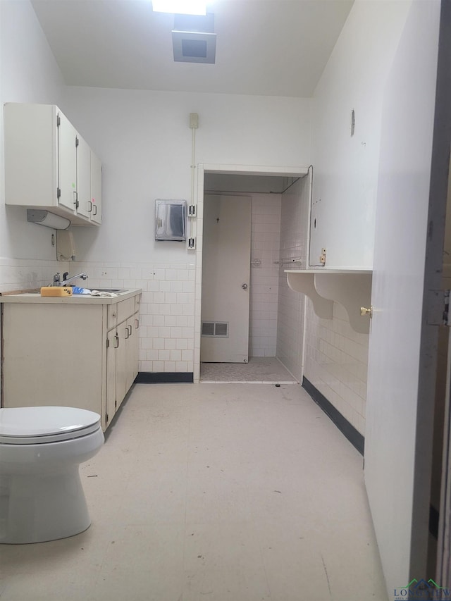 bathroom featuring sink, tile walls, and toilet