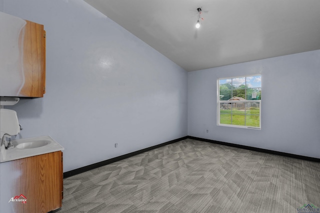 spare room featuring light carpet, sink, and vaulted ceiling