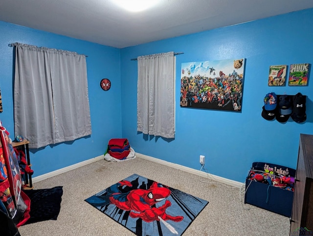 recreation room featuring baseboards and carpet