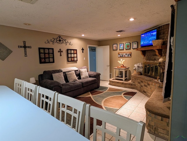 living area with a brick fireplace, recessed lighting, visible vents, and a textured ceiling