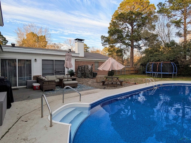 pool featuring a patio area, an outdoor living space, a trampoline, and fence