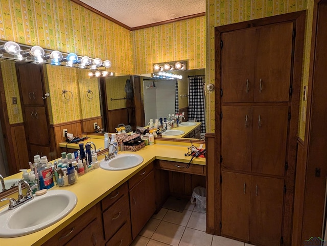 bathroom with a textured ceiling, wallpapered walls, and a sink