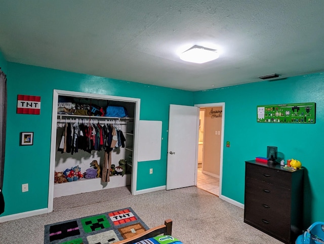 carpeted bedroom with a closet, visible vents, a textured ceiling, and baseboards