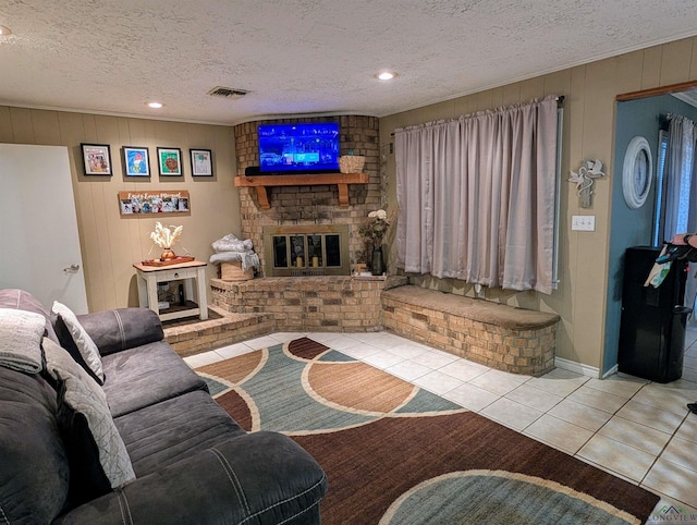 tiled living room featuring visible vents, a brick fireplace, and a textured ceiling