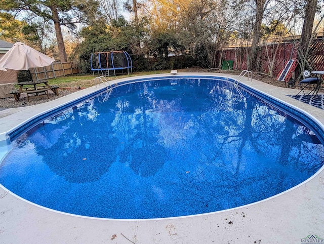 view of pool featuring a fenced in pool, a patio, a trampoline, and a fenced backyard