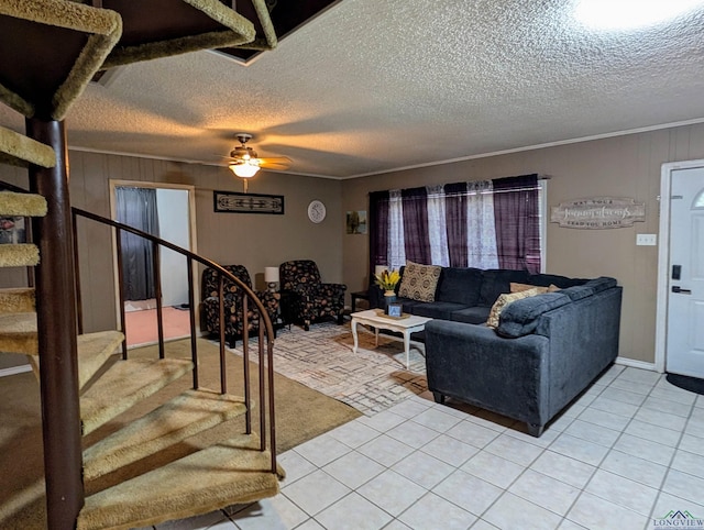 living area featuring a textured ceiling, stairway, crown molding, light tile patterned floors, and ceiling fan