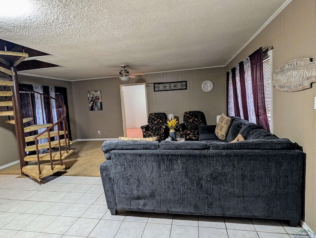 living area featuring crown molding, ceiling fan, stairs, light tile patterned floors, and a textured ceiling