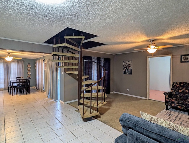 living area with light tile patterned floors, crown molding, stairs, and a ceiling fan