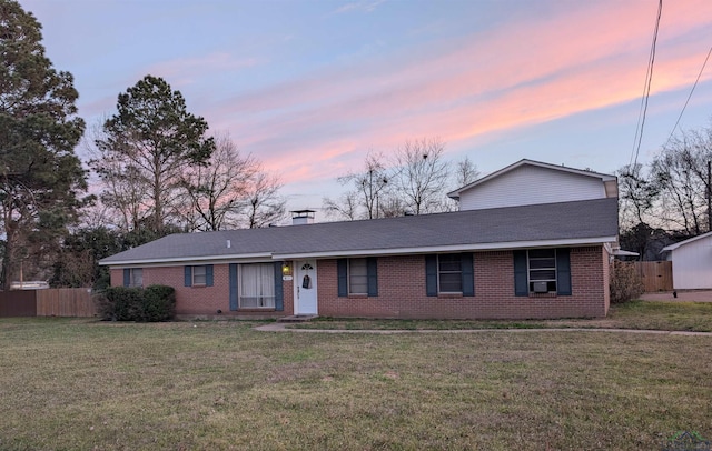 view of front of home featuring brick siding, fence, roof with shingles, a lawn, and a chimney