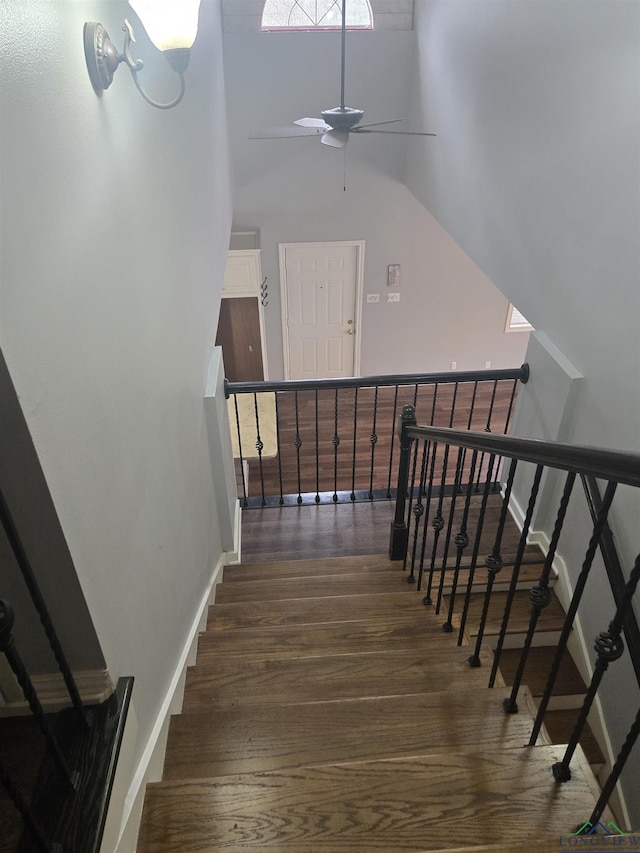 stairway with wood-type flooring and a high ceiling