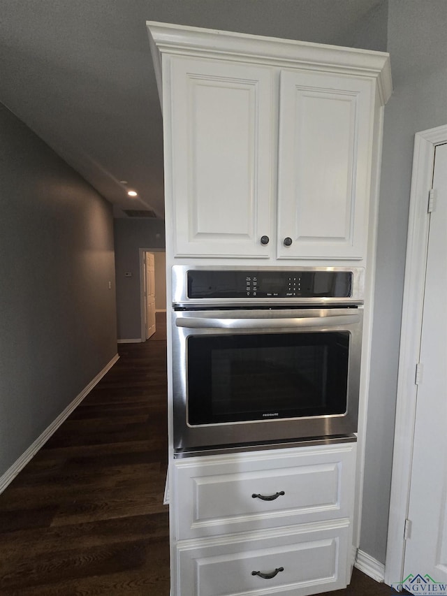 kitchen with dark hardwood / wood-style flooring, oven, and white cabinets