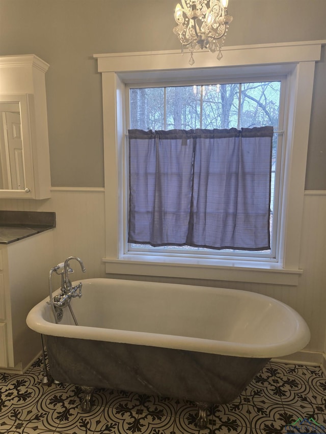 bathroom with a notable chandelier, a bathtub, and tile patterned floors