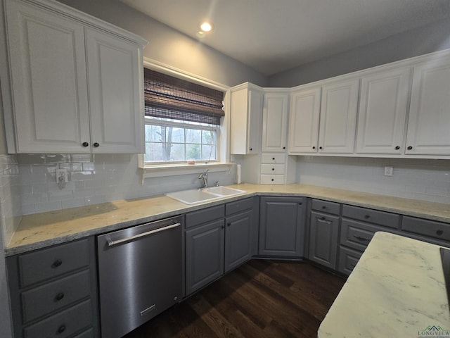 kitchen with tasteful backsplash, white cabinetry, sink, stainless steel dishwasher, and dark wood-type flooring